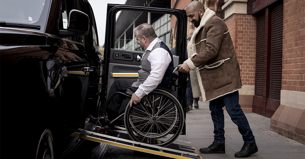 Personne âgée aidée à monter dans un taxi adapté pour un transport médical dans le Var